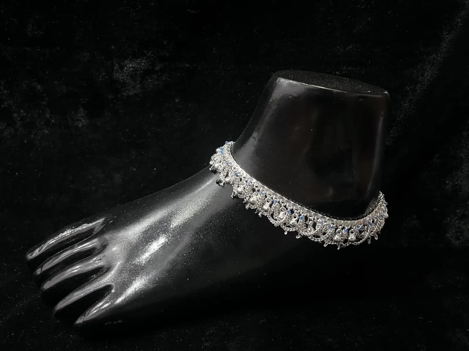 A hand-linked silver payal on a display foot
